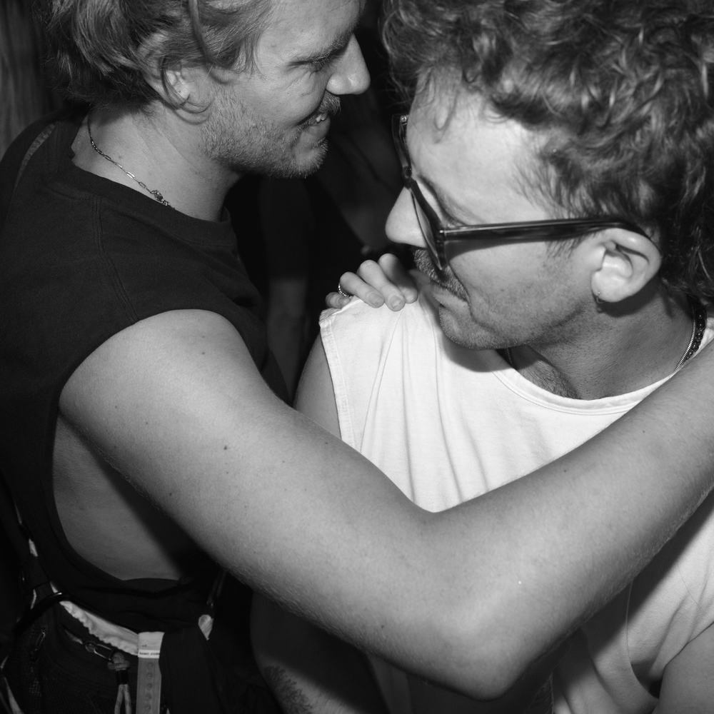 Two friends hugging on a packed King Kong Kicks dancefloor, black and white flash photo