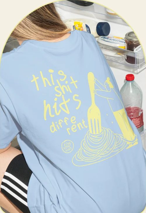 Light blue This Shit Hits Different T-shirt with a yellow spaghetti and fork drawing on the back